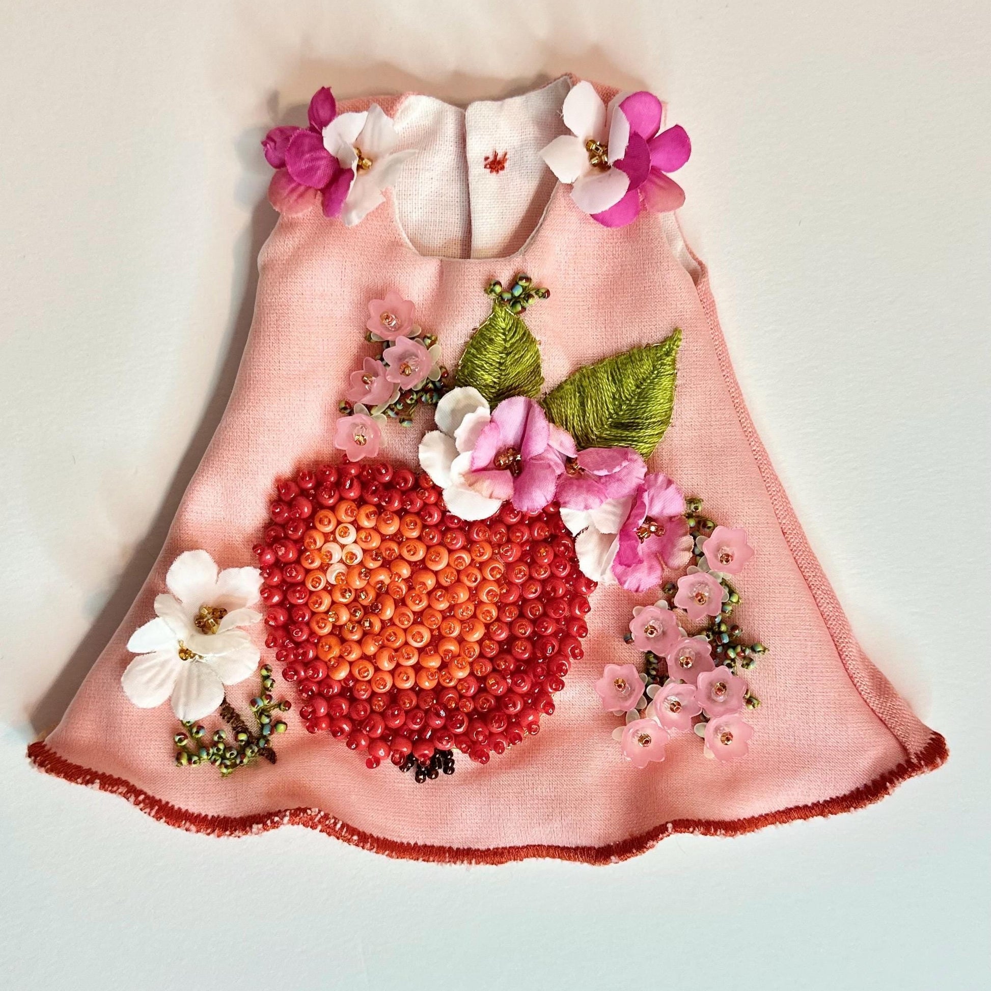 Pink doll dress with floral and berry design on a light background